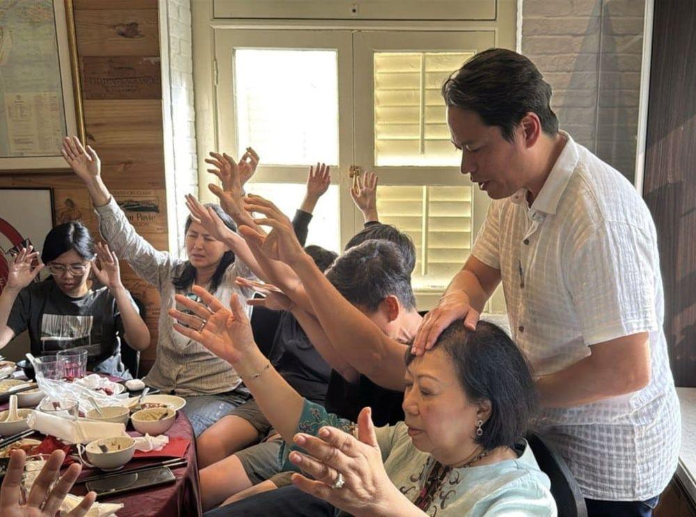 Pastor Steve Cioccolanti praying over partners at a Singapore ministry dinner